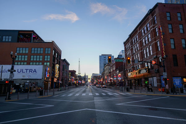 Bustling Broadway Street in Nashville at dusk with neon honky-tonk signs